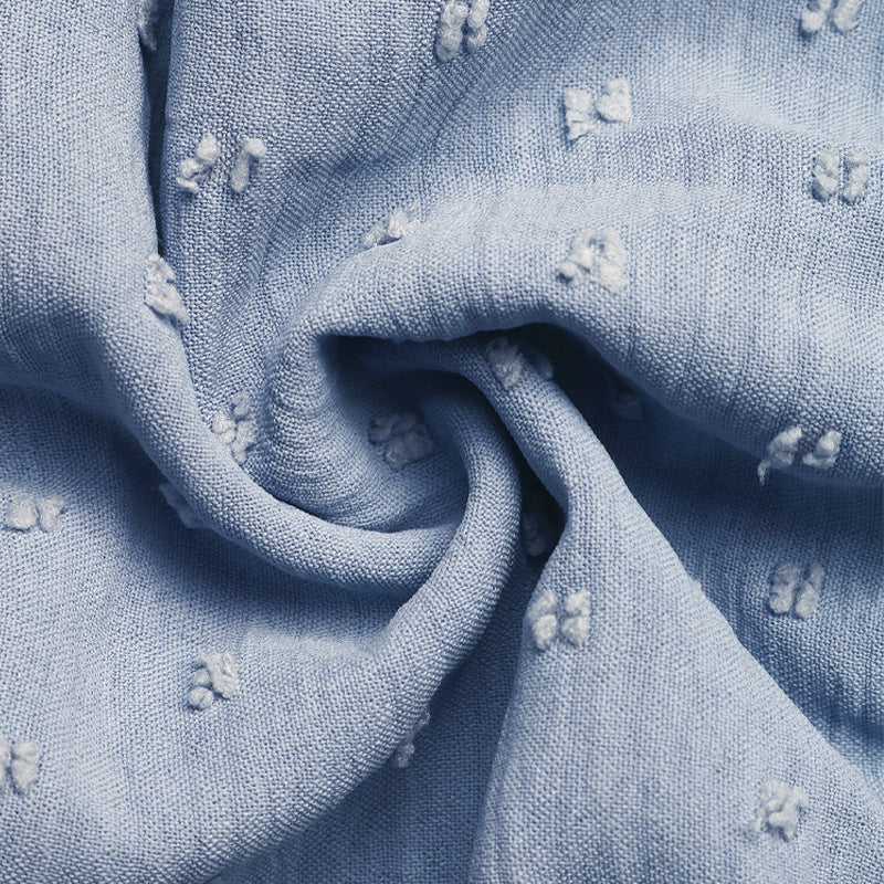 Close-up of baby blue textured fabric with delicate embroidered details.