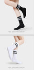 A model is wearing black and white striped athletic crew socks, posing with legs crossed against a white background
