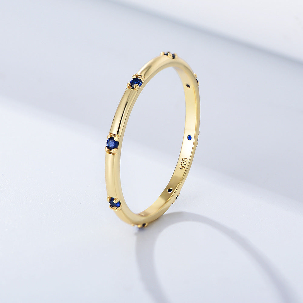 Dainty gold ring with small blue sapphires set in evenly spaced intervals, marked 925