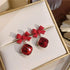 Red bow crystal earrings displayed in a gold-trimmed white jewelry box, casting shadows