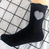 Black crew sock with gingham heart patch displayed on grid, showing ribbed texture