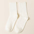 A pair of white ribbed crew socks displayed flat against cream background showing texture and full length from side angle