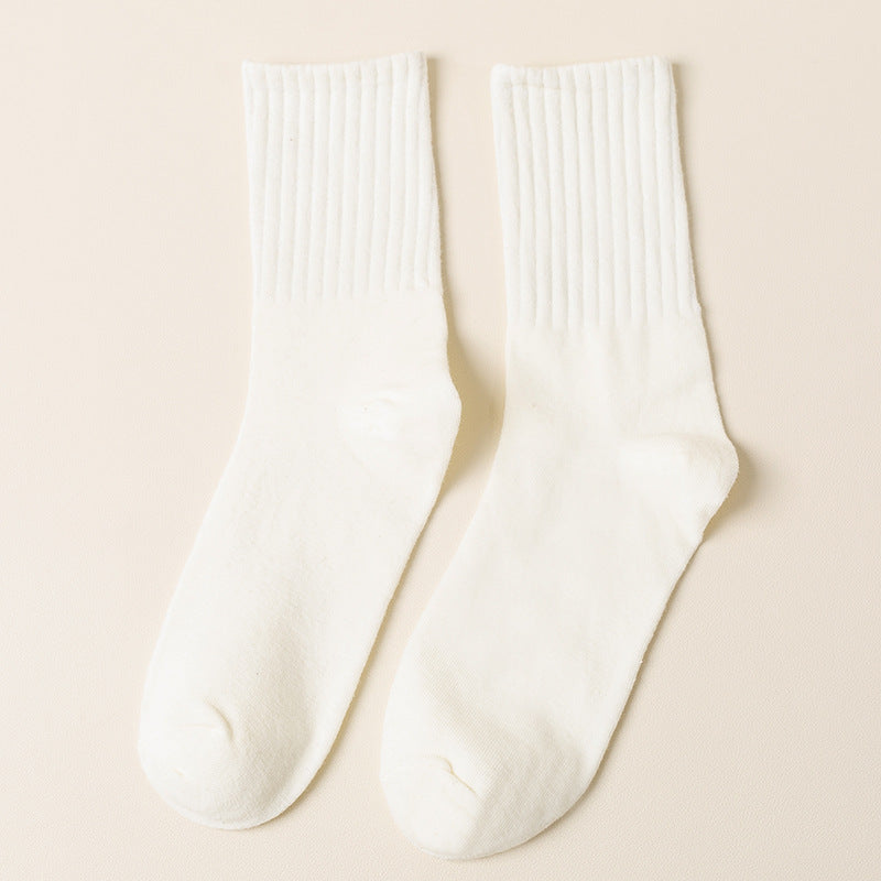 A pair of white ribbed crew socks displayed flat against cream background showing texture and full length from side angle