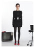 Black off-shoulder knit sweater with oversized fold-over neckline, fitted long sleeves, and cinched waist. ID badge holder on black lanyard. Front view.