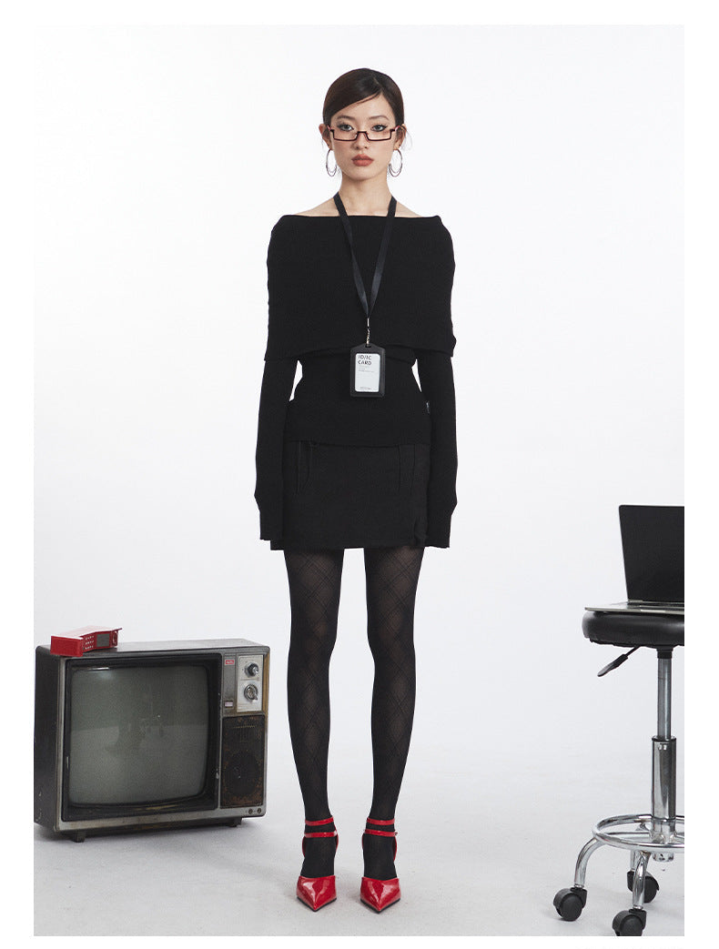 Black off-shoulder knit sweater with oversized fold-over neckline, fitted long sleeves, and cinched waist. ID badge holder on black lanyard. Front view.