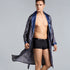 Man in open navy patterned robe wearing black boxer briefs. Close-up shows flowing silhouette and branded waistband against light gray studio background