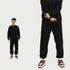 Model in forest green hoodie and matching sweatpants with white sneakers and gold accessories against white background