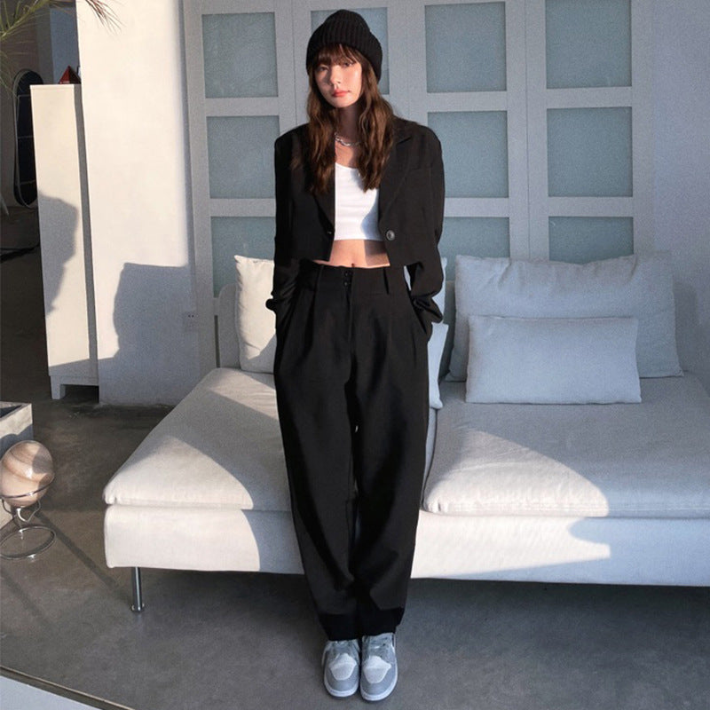 Woman wearing black suit set with crop top and wide pants, styled with beanie and sneakers