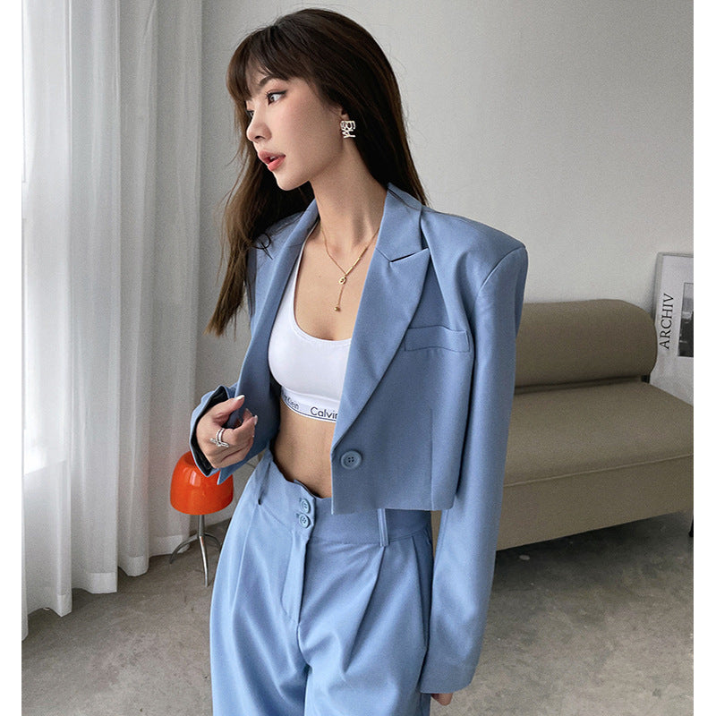 Woman in light blue cropped blazer and high-waist pants with white sports bra