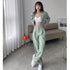Woman in mint green suit set with white sports bra and sneakers in minimal room setting