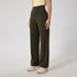 A woman wearing dark olive high-waisted wide-leg pants with a yellow crop top and cream chunky sneakers, standing against a white background