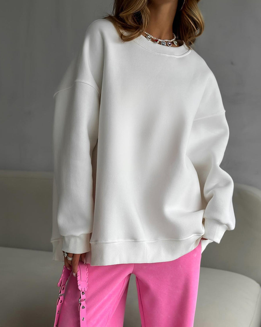 White oversized sweatshirt with pink pants – Model wears a loose-fit white sweatshirt styled with pink pants and a silver necklace