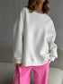 White oversized sweatshirt with pink pants – Model wears a loose-fit white sweatshirt styled with pink pants and a silver necklace