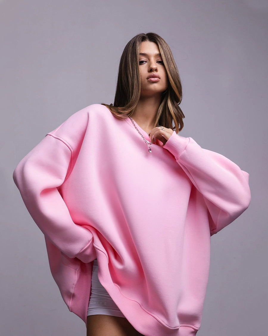 Pink oversized sweatshirt dress – Model in a pastel pink oversized sweatshirt, worn as a dress, accessorized with a silver necklace