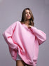 Pink oversized sweatshirt dress – Model in a pastel pink oversized sweatshirt, worn as a dress, accessorized with a silver necklace