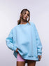 Sky blue oversized sweatshirt dress – Model wears a pastel blue oversized sweatshirt with pink shorts, accessorized with a choker necklace