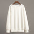 White oversized sweatshirt on hanger – A plain white oversized sweatshirt displayed on a wooden hanger against a neutral background
