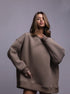 Brown oversized sweatshirt dress – Model in a taupe oversized sweatshirt dress, styled with silver jewelry for a relaxed streetwear look