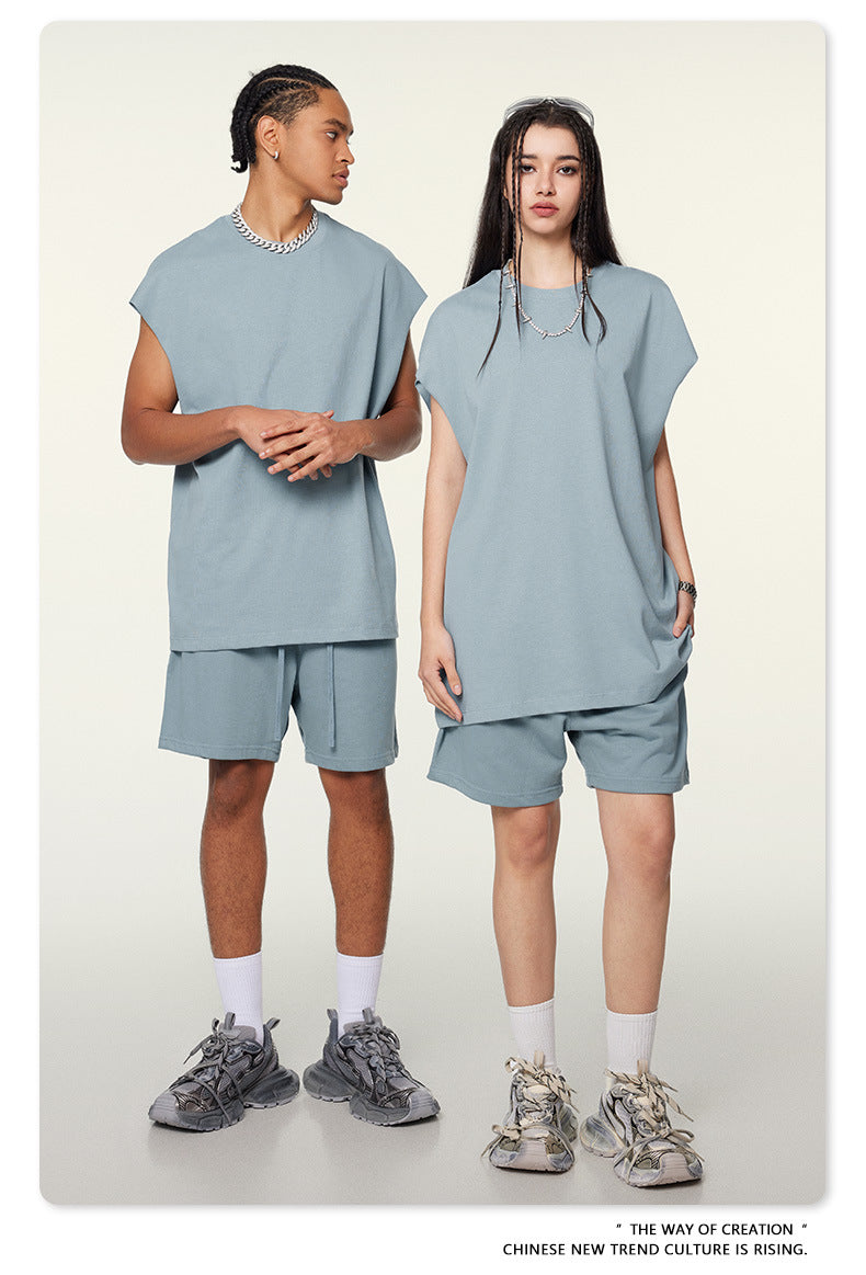 Male and female models wearing matching powder blue oversized tee and shorts sets with white socks and sneakers