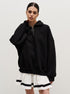 Woman wearing black oversized quarter-zip sweatshirt with ring pull and white pleated tennis skirt with black stripes