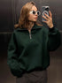 Mirror selfie of woman in forest green quarter-zip sweatshirt and white sunglasses in elevator