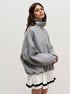 Woman wearing grey quarter-zip sweatshirt with white pleated tennis skirt and black stripe detailing