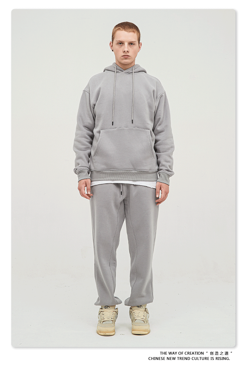 Male model with short hair wearing a light gray sweatsuit with hoodie, white undershirt, and matching joggers