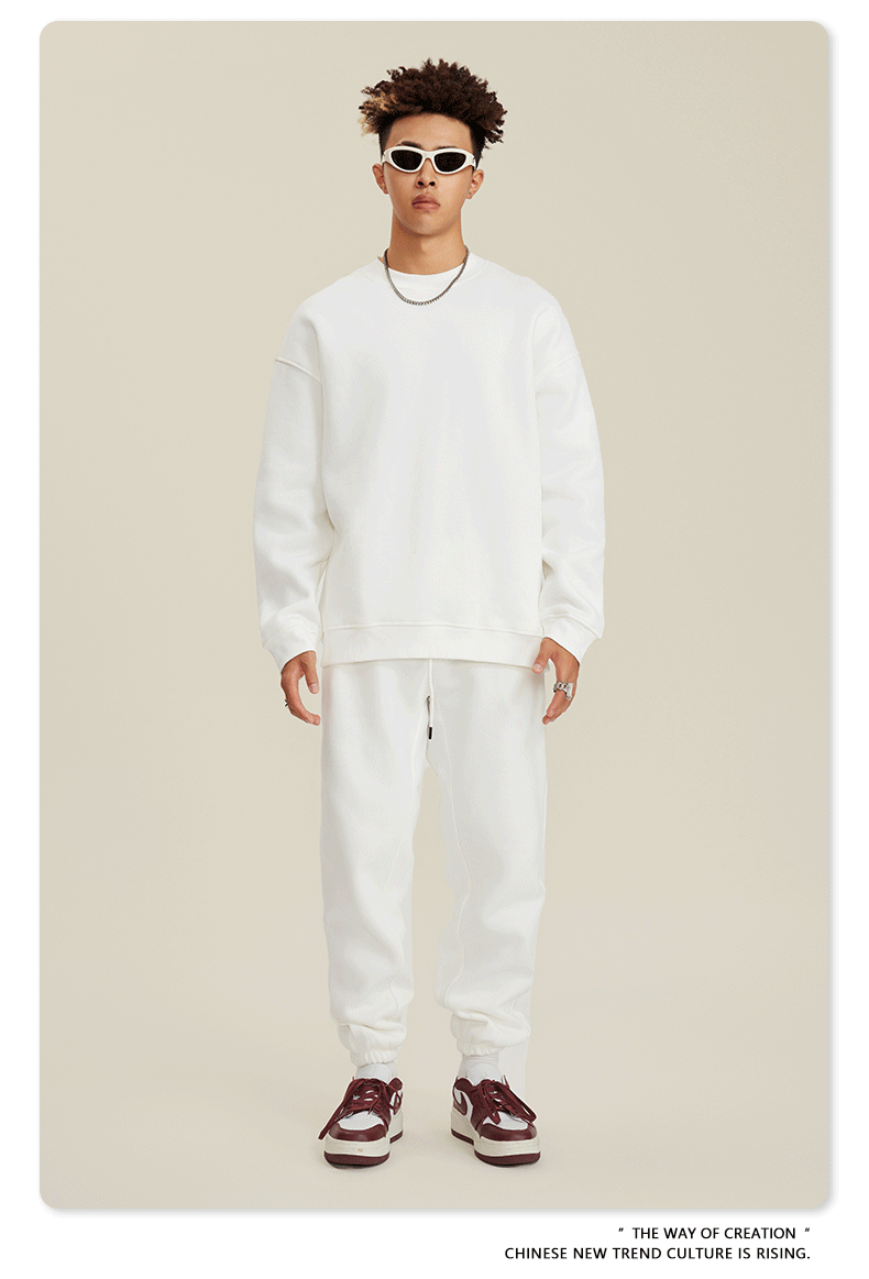 Model in white sweatsuit with white sunglasses, silver chain necklace and Nike high-tops