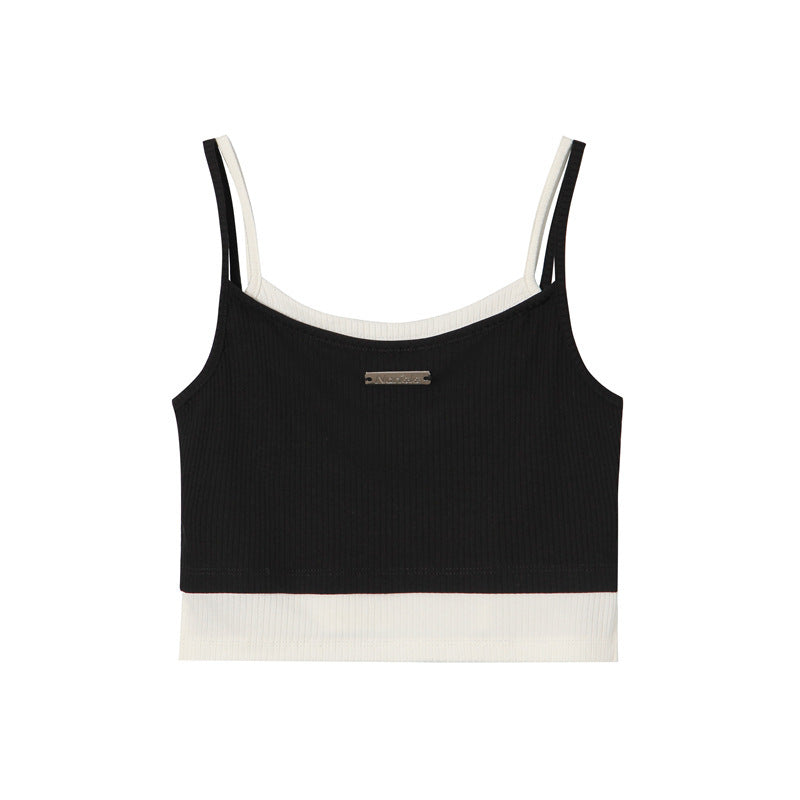 A black ribbed crop tank with white contrast trim and small metal logo plate, displayed flat against white background