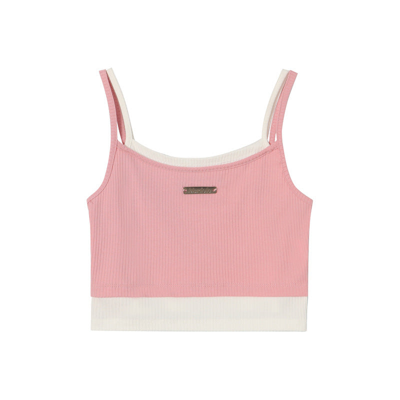 A pink ribbed crop tank with white contrast trim and small metal logo plate, displayed flat against white background