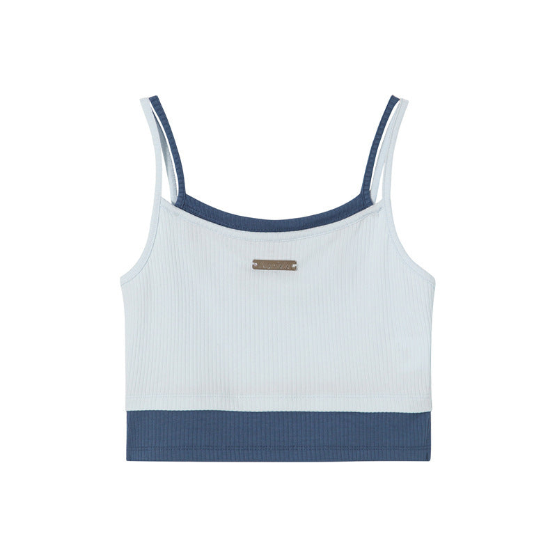 A white ribbed crop tank with navy blue contrast trim and small metal logo plate, displayed flat against white background