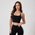 A woman is posing with one hand down wearing a black sports bra with white trim detail and high-waisted leggings with side stripes