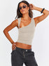 Beige/cream one-shoulder top with black sunglasses and studded belt