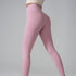 Model in soft pink high-waisted athletic leggings and cream top, side pose, gold nails visible against gray backdrop