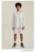 Man in white sweatshirt and shorts set with chain necklace, red-detail watch and sneakers
