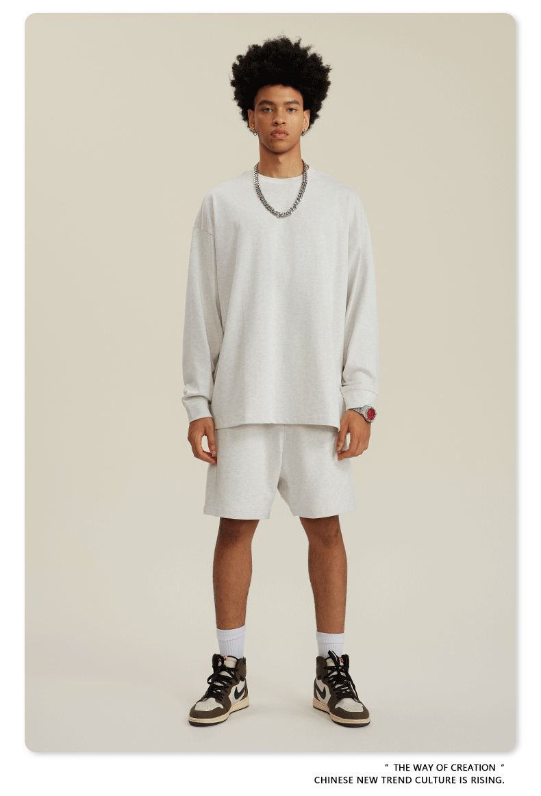 Man in white sweatshirt and shorts set with chain necklace, red-detail watch and sneakers