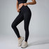 A model wearing black high-waisted leggings and crop top, demonstrating waistband stretch against gray backdrop
