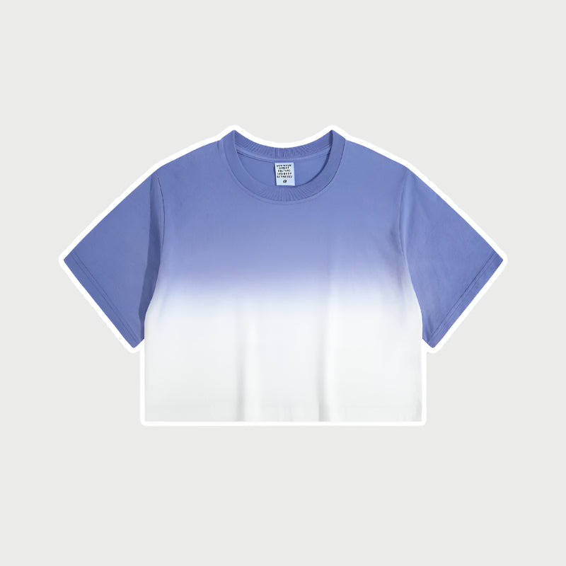 Purple and white ombré cropped short-sleeve t-shirt with gradual color fade from deep blue to white, featuring a crew neck and a small branded tag at the collar