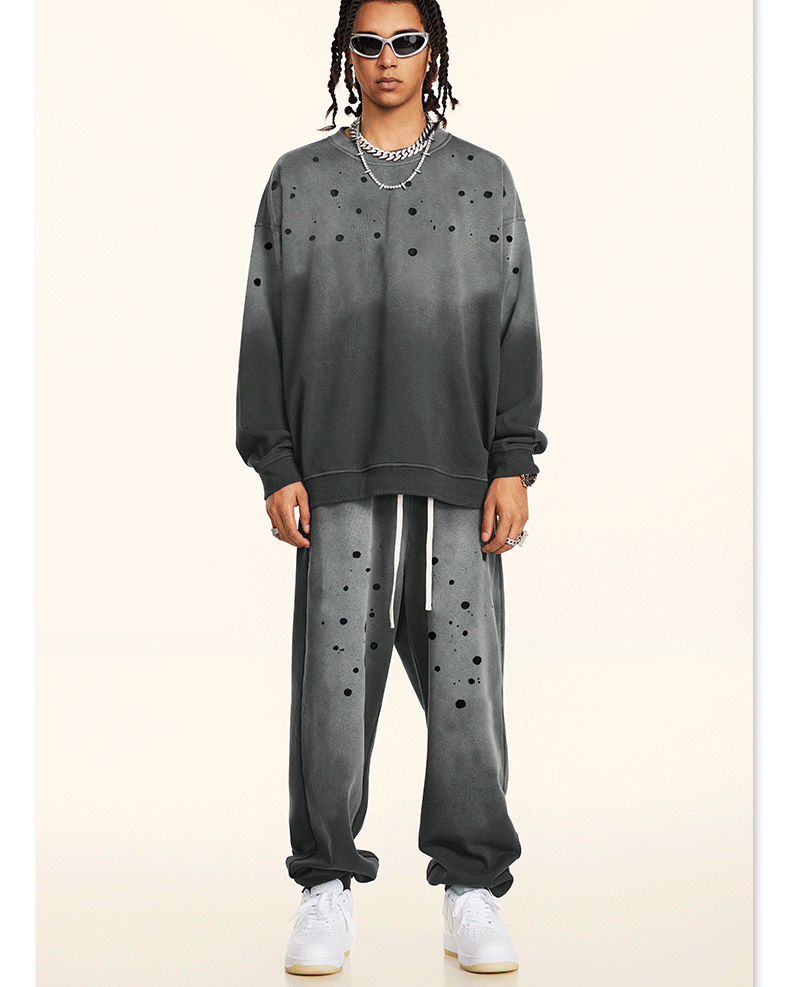 GIF showing model rotating to display gray splatter-print sweatsuit with silver chains and white sneakers