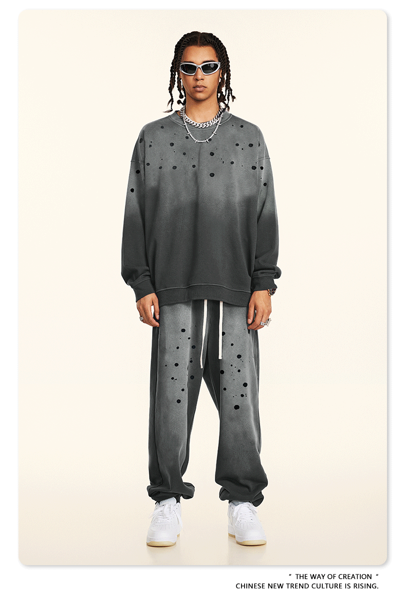 GIF showing model rotating to display gray splatter-print sweatsuit with silver chains and white sneakers