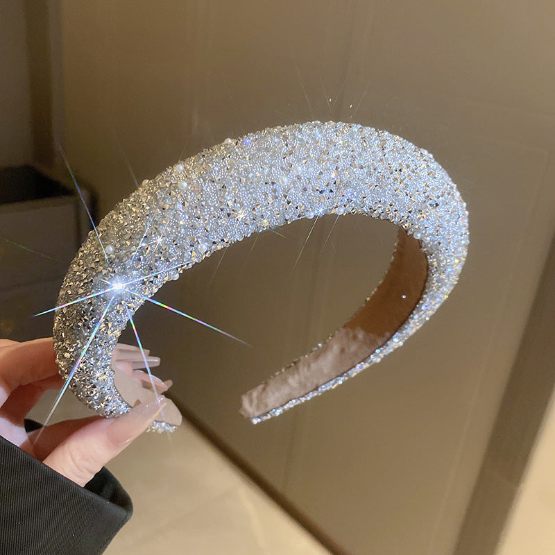 Luxurious white-tone headband with densely packed rhinestones, reflecting intense light for a glamorous, statement look.