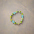 A vibrant beaded bracelet with green and turquoise beads, featuring turquoise cross-shaped beads and metallic green cross accents