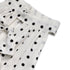  Side angle close-up of the neckline and upper bodice of a white polka dot halter dress with ruffle bow details.