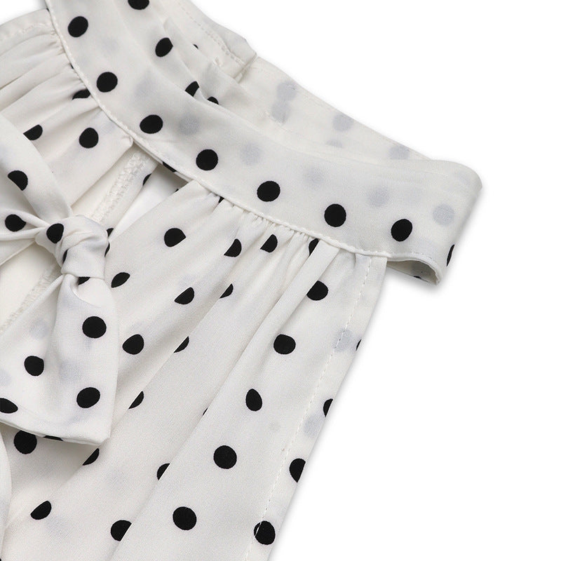  Side angle close-up of the neckline and upper bodice of a white polka dot halter dress with ruffle bow details.