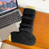 Black ribbed leg warmer displayed on yellow cardholder next to MacBook laptop on wooden desk