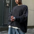 Grey oversized sweater layered over white t-shirt with jeans, urban industrial background with signage