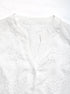Close-up of V-neck button-up design on white embroidered blouse, highlighting fine stitching and delicate lace detailing.
