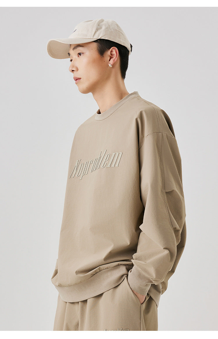 Side view of the beige "NoProblem" oversized sweatshirt, with the model casually placing his hands in his pockets