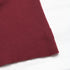 Close-up of the hemline of the burgundy ribbed top, showcasing the fine knit fabric.

