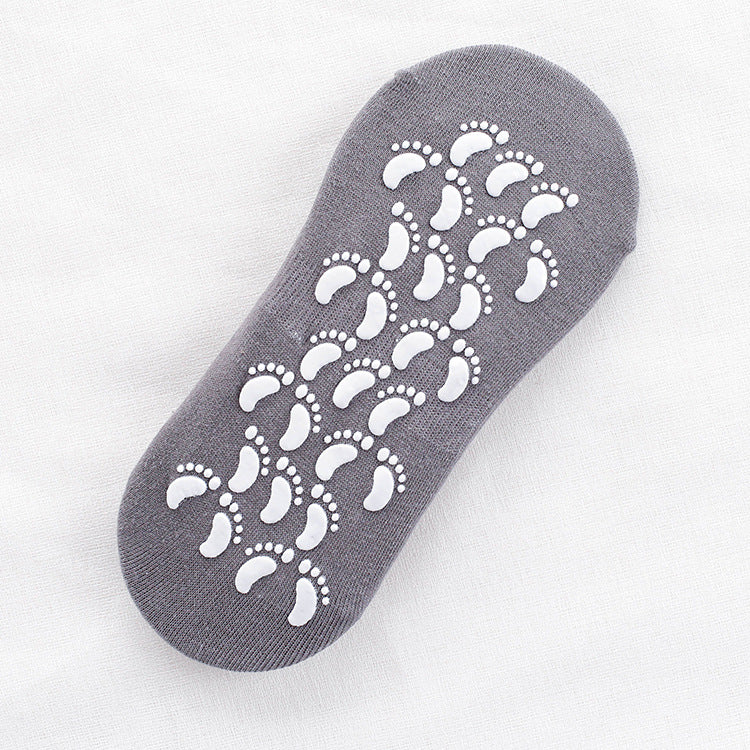 Gray non-slip ankle sock with white footprint grip pattern on sole displayed flat against white fabric background
